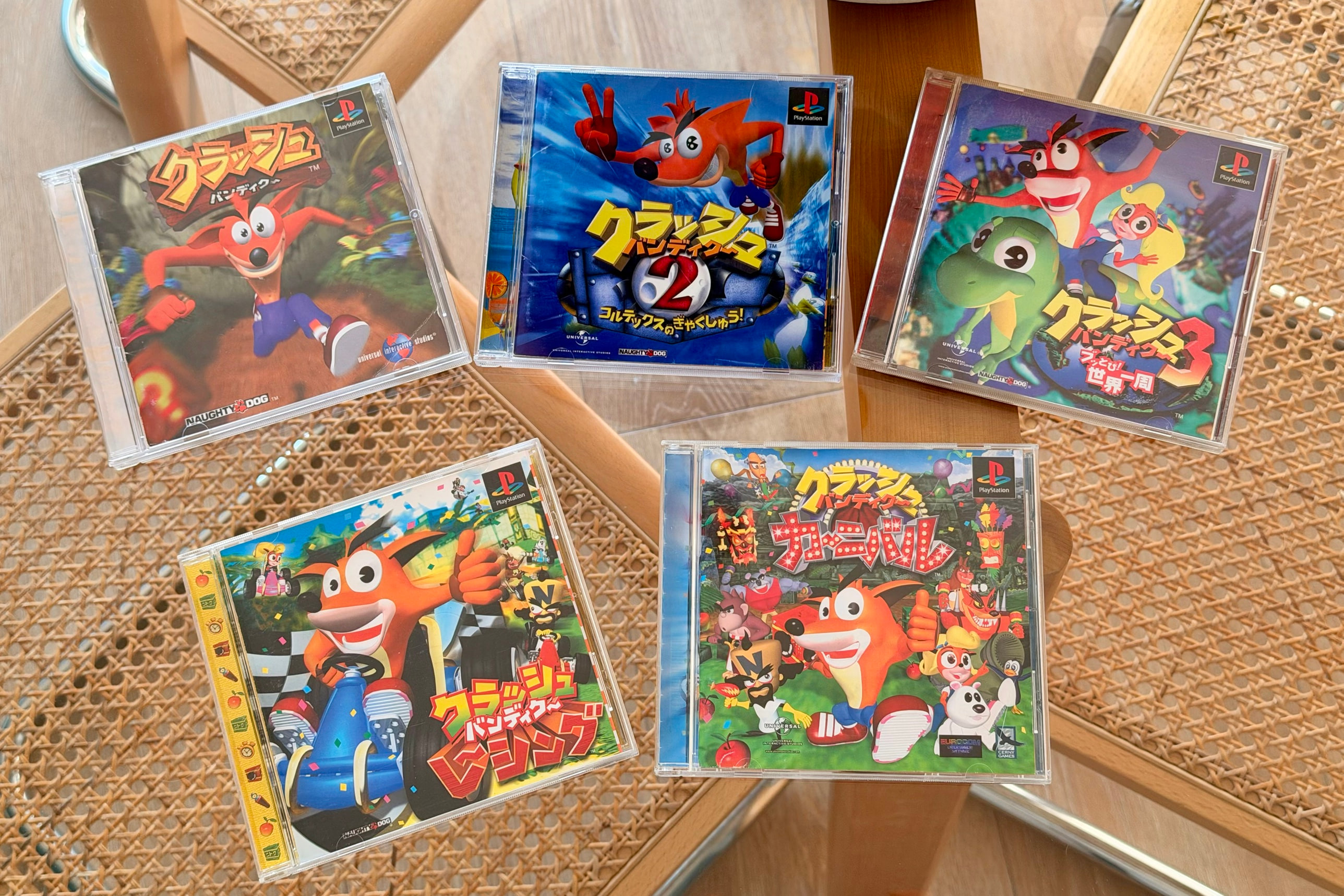 Five Japanese Crash Bandicoot games in their jewel cases, laid out on a table: 1, 2, 3, Racing and Carnival