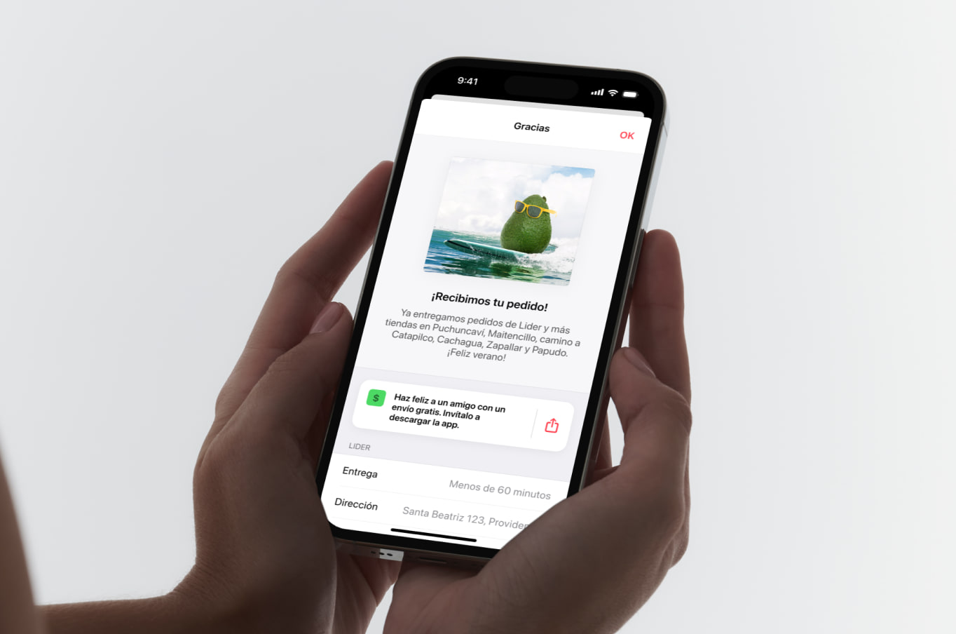 Two hands holding an iPhone on the screen that follows an order: an avocado in sunglasses surfing a wave, over “¡Recibimos tu pedido!” and a note that Cornershop now delivers to the towns up the coast.
