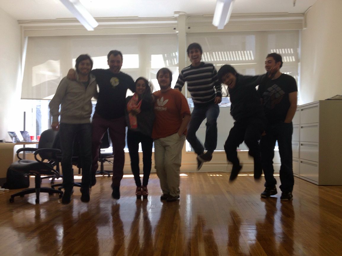 The Seahorse team in the office, lined up against the windows, two of them caught mid-jump.
